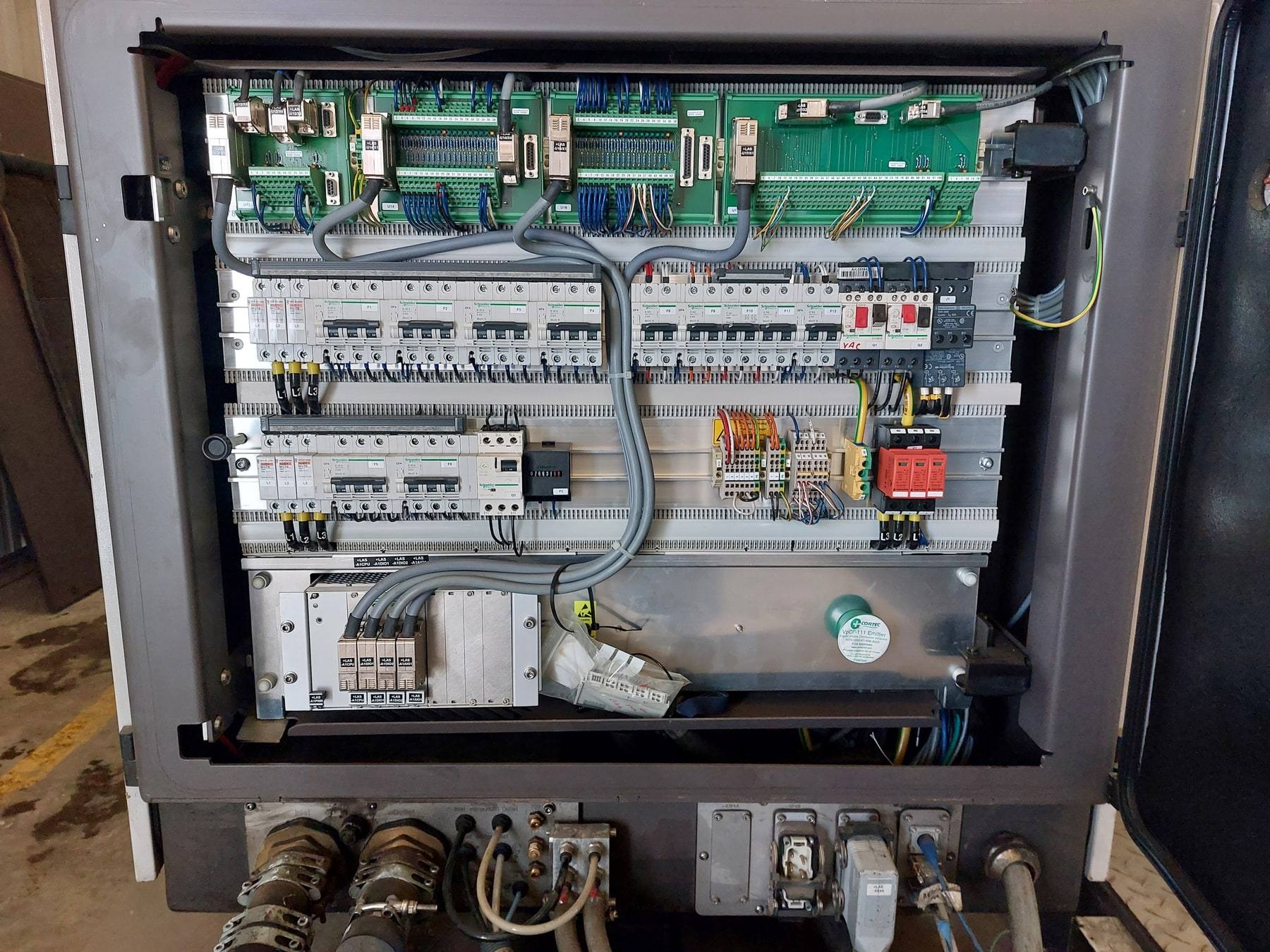 Open industrial control cabinet with circuit breakers, terminal blocks, I/O modules and field wiring.