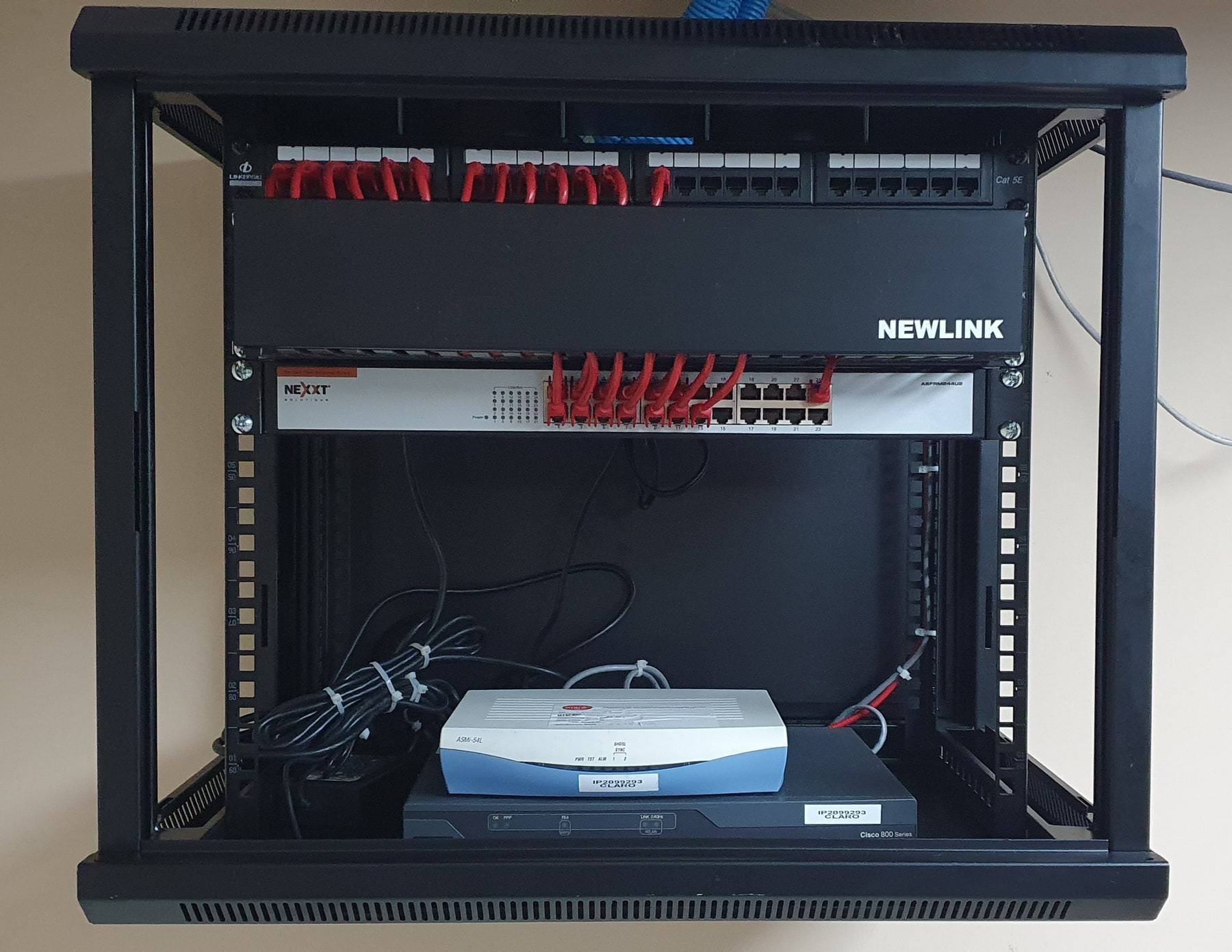 Wall-mounted network cabinet with a patch panel, access switch, cable manager and a Cisco router.